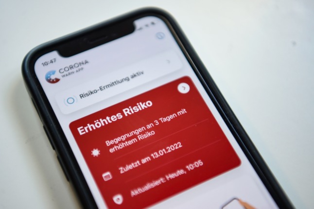 The Corona-Warn app shows a red Covid alert.