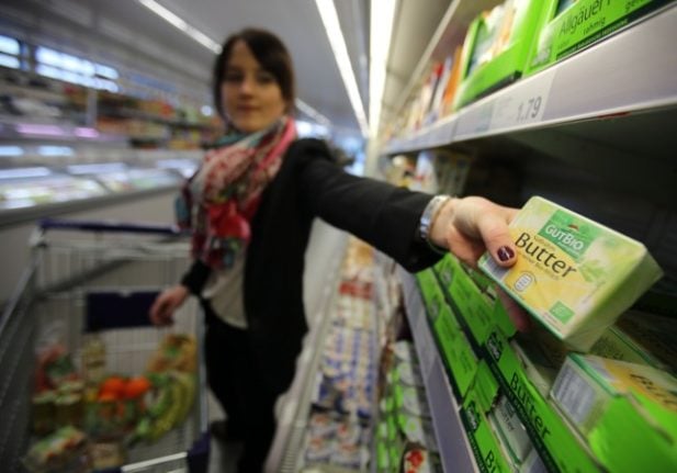 A woman takes butter off a shelf in a German supermarket. 