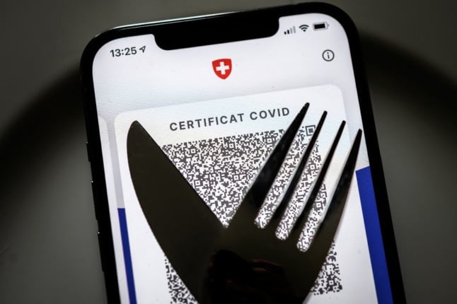 Will the Covid certificate requirement remain in place anywhere? A illustration picture taken on September 14, 2021 in Lausanne shows a Swiss Covid certificate displayed on a smartphone and a fork and knife, as Switzerland decided to widely extend the obligation of health pass, facing a pandemic of Covid-19 which continues to fill the hospitals and the beds of intensive care and an insufficient rate of vaccination. - From September 13, 2021, it is necessary to show its Covid certificate to enter a restaurant or a bar, enter in an exhibition place, cinema's or a sporting event indoors. (Photo by Fabrice COFFRINI / AFP)