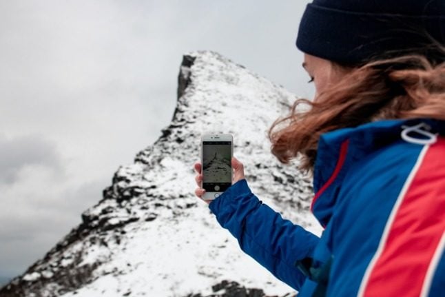 Somebody taking pictures of a mountaintop in Norway using their smartphone. 