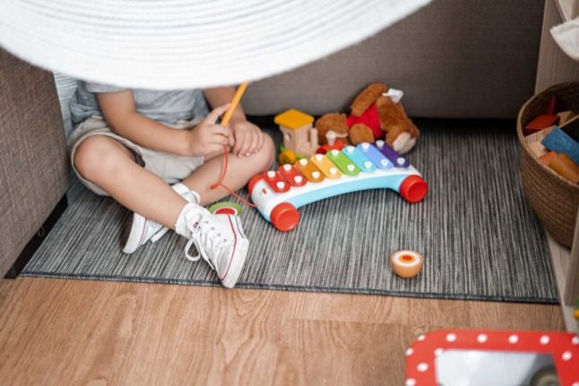 A child plays with toys behind a white curtain