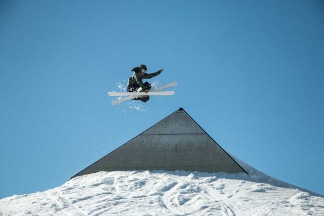 A skier gets some sweet air jumping off that fresh white pow pow over a triangle.