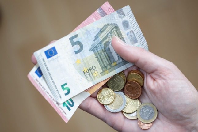 A woman holds bills and coins in her hand.