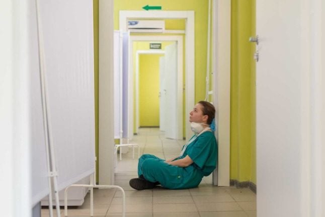 A nurse sits on the floor at a hospital 