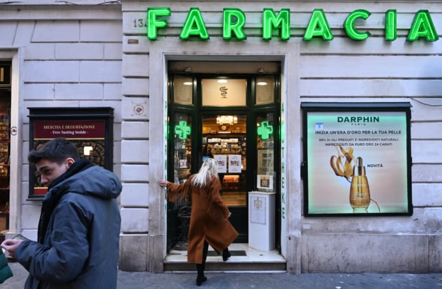 A woman enters an pharmacy in Italy.