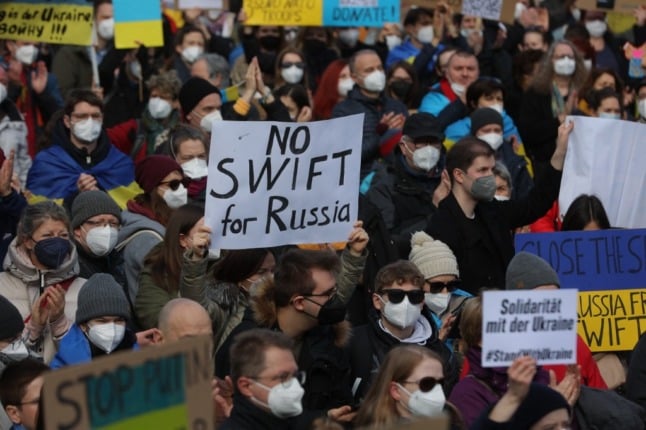 Protester in a crowd holding a placard reading 'No Swift for Russia