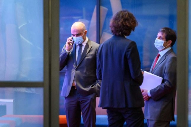 Swiss Health Minister Alain Berset on the telephone while wearing a mask. Photo: Fabrice COFFRINI / AFP