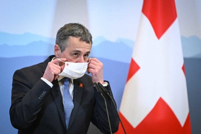 Swiss President Ignazio Cassis removes his mask. Photo: Fabrice COFFRINI / AFP