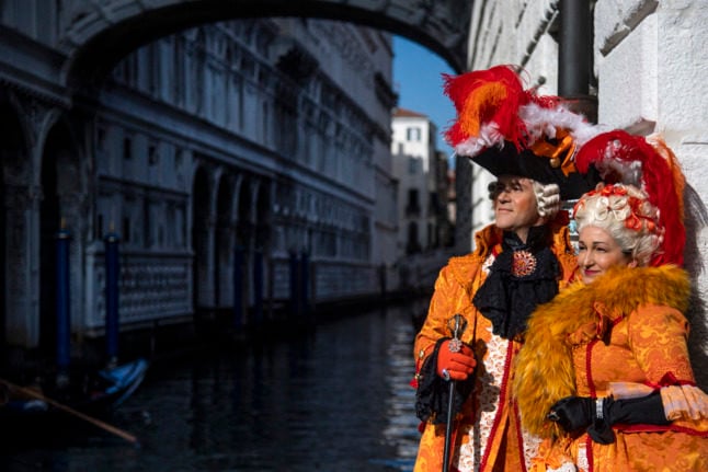 Masked revellers wearing a traditional carnival costumes pose on St Mark Square during Venice's Carnival on February 13, 2022.