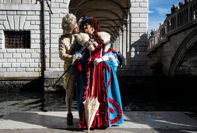 A costumed couple poses on St Mark's Square during Venice's Carnival on February 13, 2022. 