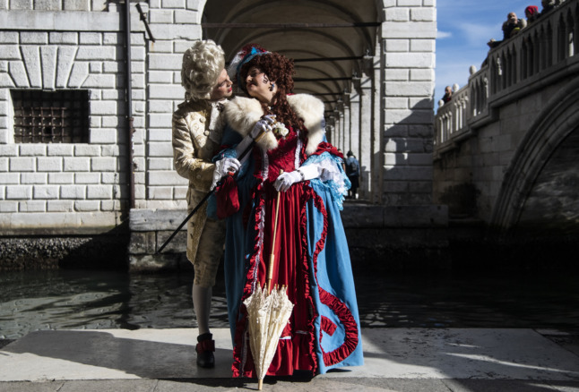 A costumed couple poses on St Mark's Square during Venice's Carnival on February 13, 2022.