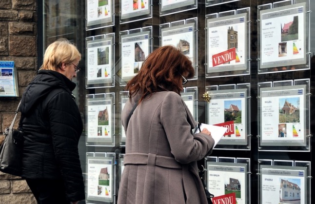 Prospective buyers peer into a real estate agency in France.