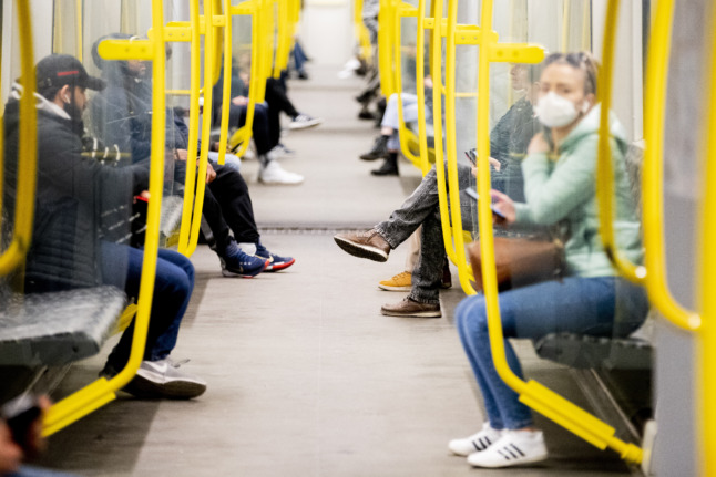 People sit on the Berlin U-Bahn wearing masks