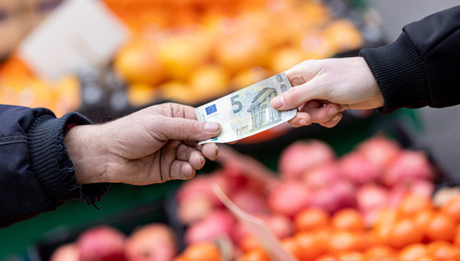 A customer in a supermarket hands over a €5 note.