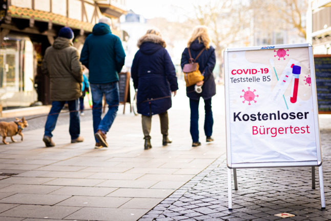 People walk past a Covid testing station sign in Braunschweig.