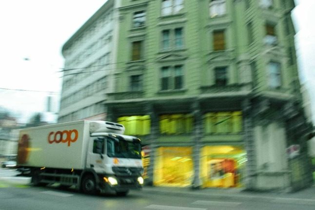 A truck from Switzerland's Coop supermarket drives through the streets. Photo by Ardian Lumi on Unsplash