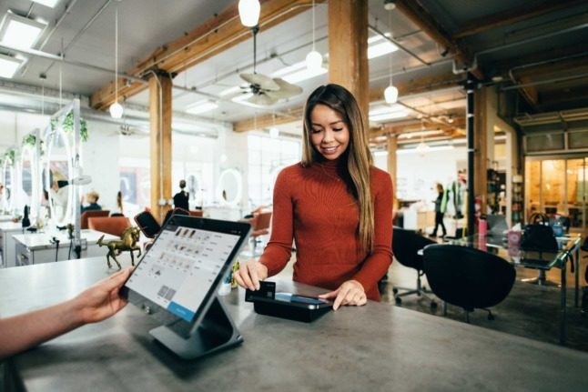 A person pays with card at a hair salon. Photo by Blake Wisz on Unsplash