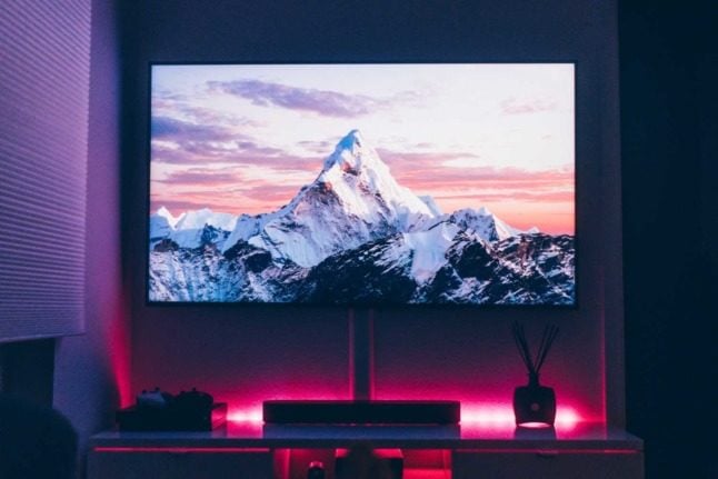 A person watches images of the alps on TV. Photo by Jan Böttinger on Unsplash