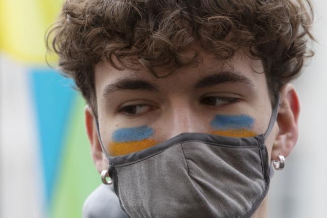 A man has Ukrainian national colours on the cheeks during a demonstration against the Russian invasion of Ukraine in Vienna