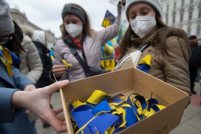 A person hands out Ukraine flags at a rally opposing Russia's invasion in Vienna. Photo: ALEX HALADA / AFP