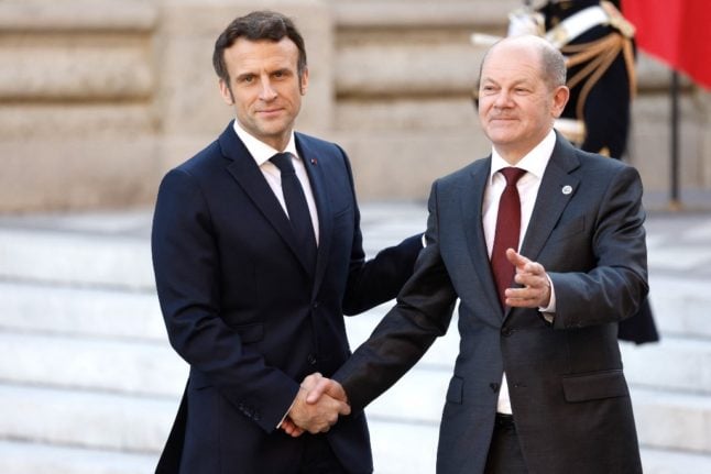 French president Emmanuel Macron and German chancellor Olaf Scholz shake hands at the Palace of Versailles