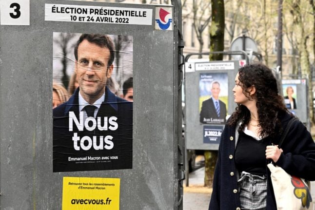 A pedestrian walks past a campaign poster of France's President and La Republique en Marche (LREM) party candidate Emmanuel Macron in Paris