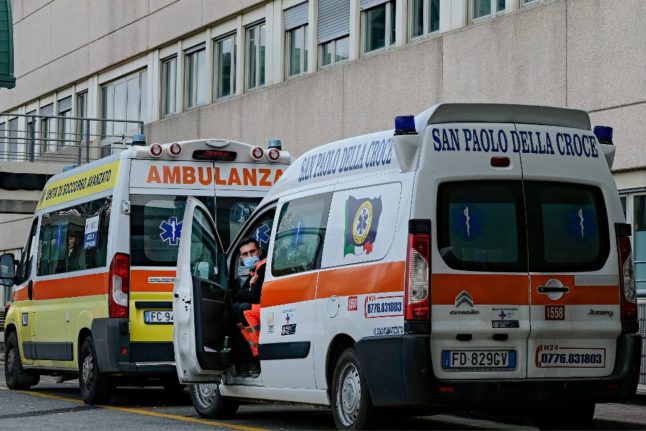 An ambulance driver waits as vehicles line up outside the main emergency access at a hospital in Italy.