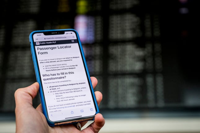 A passenger shows a shows a passenger locator form on his mobile phone at Brussels airport on January 1, 2021.