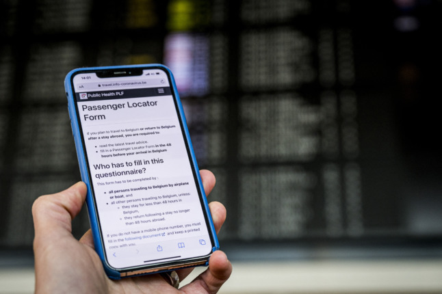 A passenger shows a shows a passenger locator form on his mobile phone at Brussels airport on January 1, 2021.