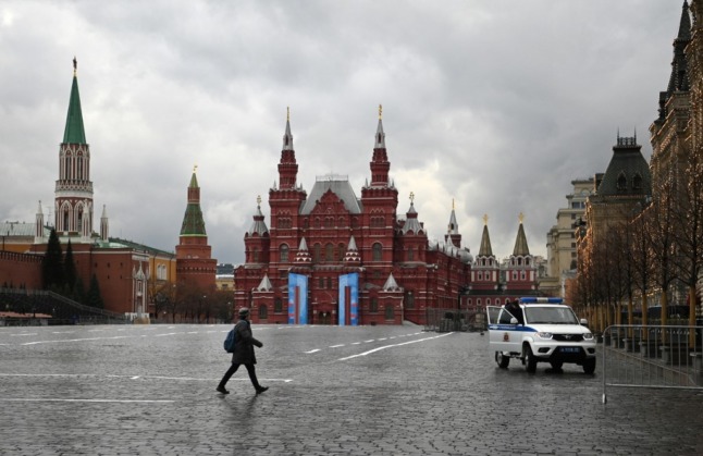 A man walks as a police car patrols at Red Square in Moscow