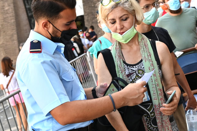 A tourist shows her green pass to an official. 