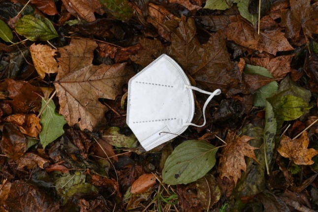 A face mask lies among the autumn leaves.