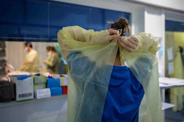 A nurse puts on protective gear in the Swiss canton of Neuchatel. Photo: Fabrice COFFRINI / AFP