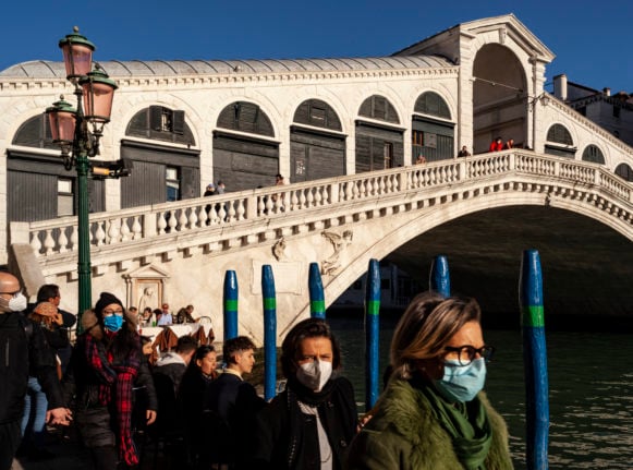 pedestrians, wearing protective face masks, walk next to the Rialto Bridge in Venice, northeastern Italy, on January 11, 2022.