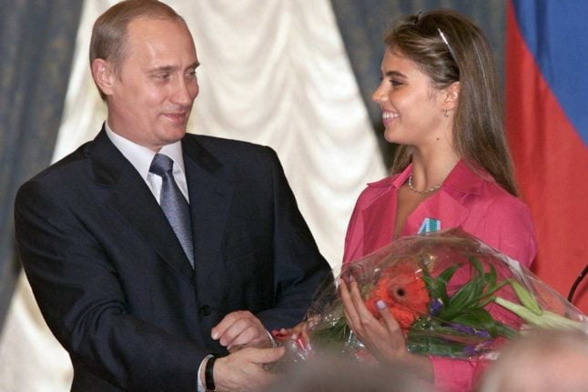 Russian President Vladimir Putin (L) hands flowers to Alina Kabayeva, Russian rhytmic gymnastics star and Olympic prize winner, after awarding her with an Order of Friendship during annual award ceremony in the Kremlin 08 June 2001. Photo: SERGEI CHIRIKOV / POOL / AFP