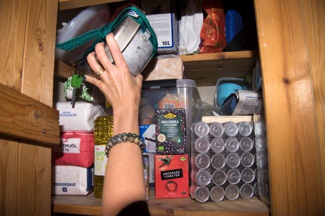 A person packs a camping stove into a cupboard full of emergency items.