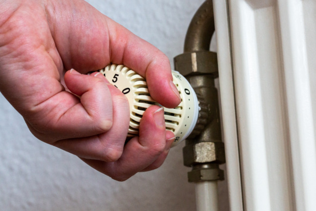 A person changing the heating setting on a radiator. The coalition has pledged financial support people in Germany.