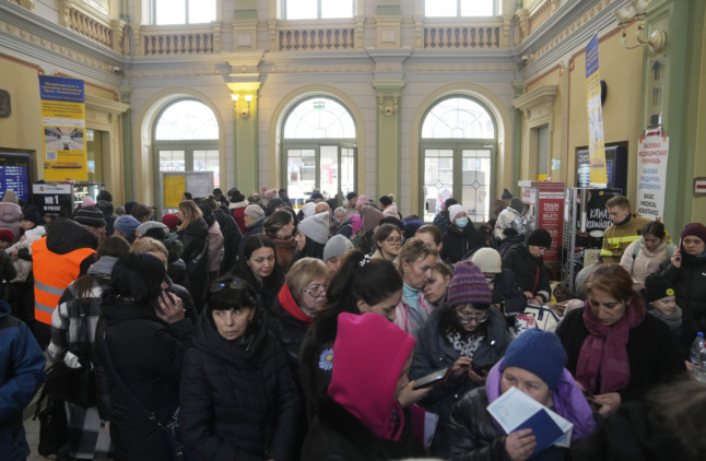 People fleeing Ukraine queue for information about trains and tickets at a train station in Przemysl, Poland.