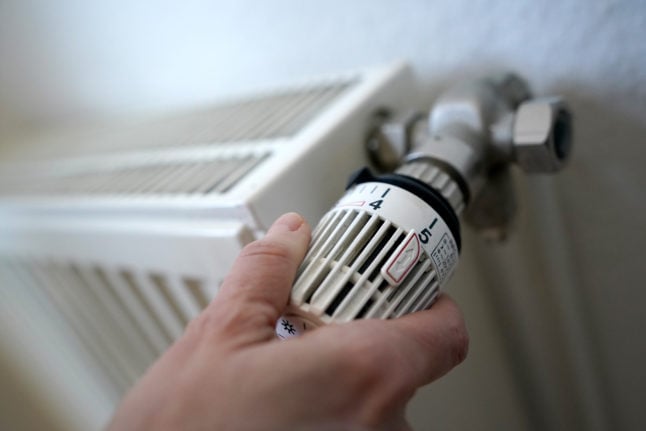 A woman adjusts the thermostat on her radiator.