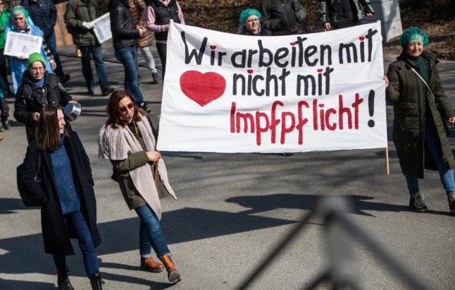 Demonstrators against Covid vaccine mandates carry a sign that reads 'we work with heart, not compulsory vaccination, during a protest in Crailsheim, Baden-Württemberg on March 12th.