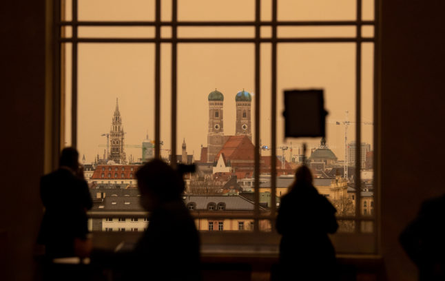 People stand in front of a window in the Bavarian parliament as Sahara dust gathered over the city centre on Tuesday, colouring the sky a yellow/orange colour.
