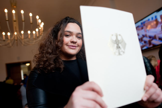 A woman shows the booklet with her naturalisation certificate at Neukölln town hall in Berlin in April 2016.