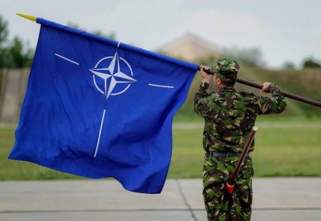 A soldier waves a Nato flag