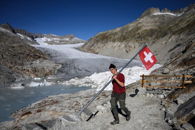 A man carries a Swiss flag. 