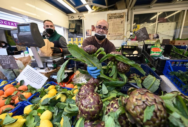 A fruit and vegetable seller picks artichokes at the Testaccio market Rome. 