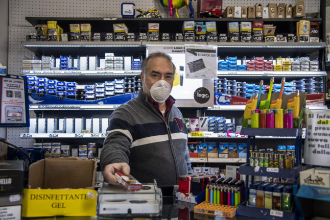 A tobacco seller wearing a face mask is pictured at his counter on March 23, 2020 in the Prati district of Rome, during the COVID-19 new coronavirus pandemic.