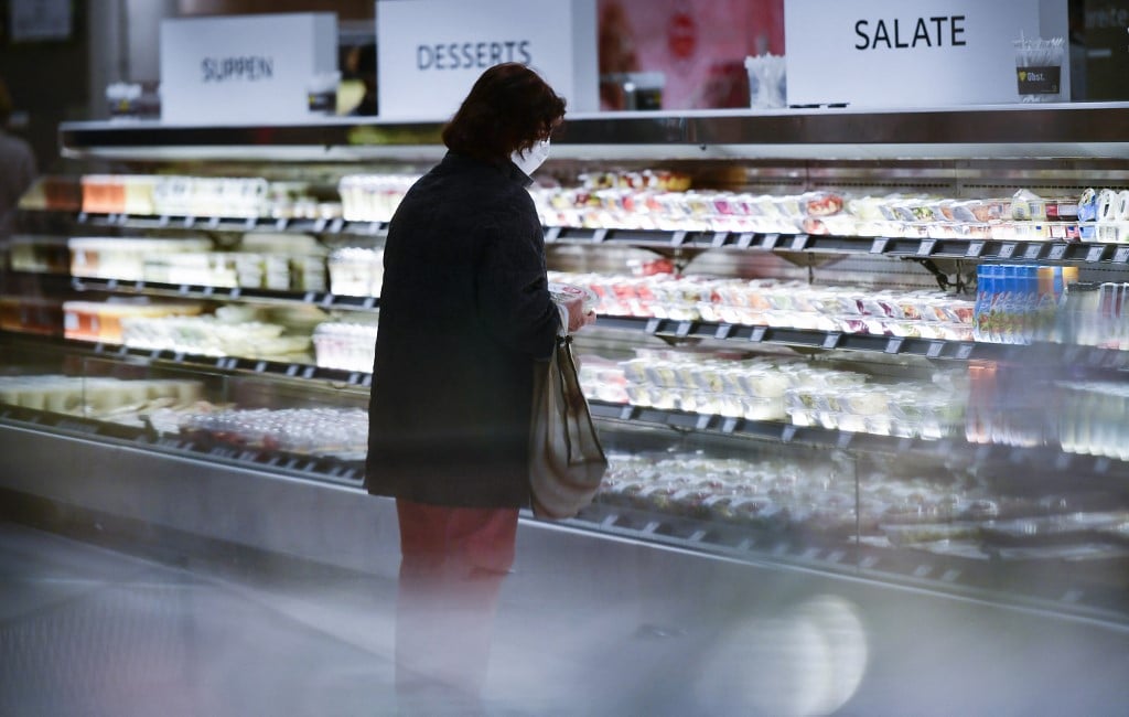 A customer wearing a face mask makes purchases at a German supermarket