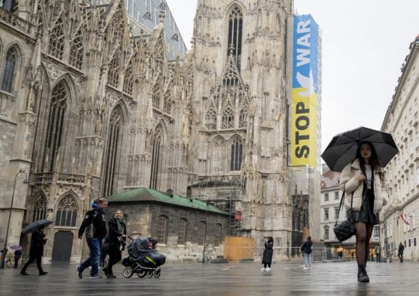 People walk past Saint Stephen's cathedral displaying a 'Stop War' banner on a rainy day in Vienna, Austria in 2022.