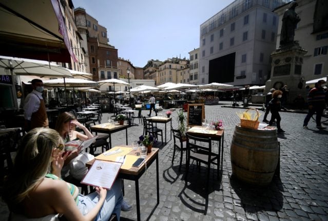 People eat a lunch in a restaurant in Campo dei Fiori square in downtown Rome.