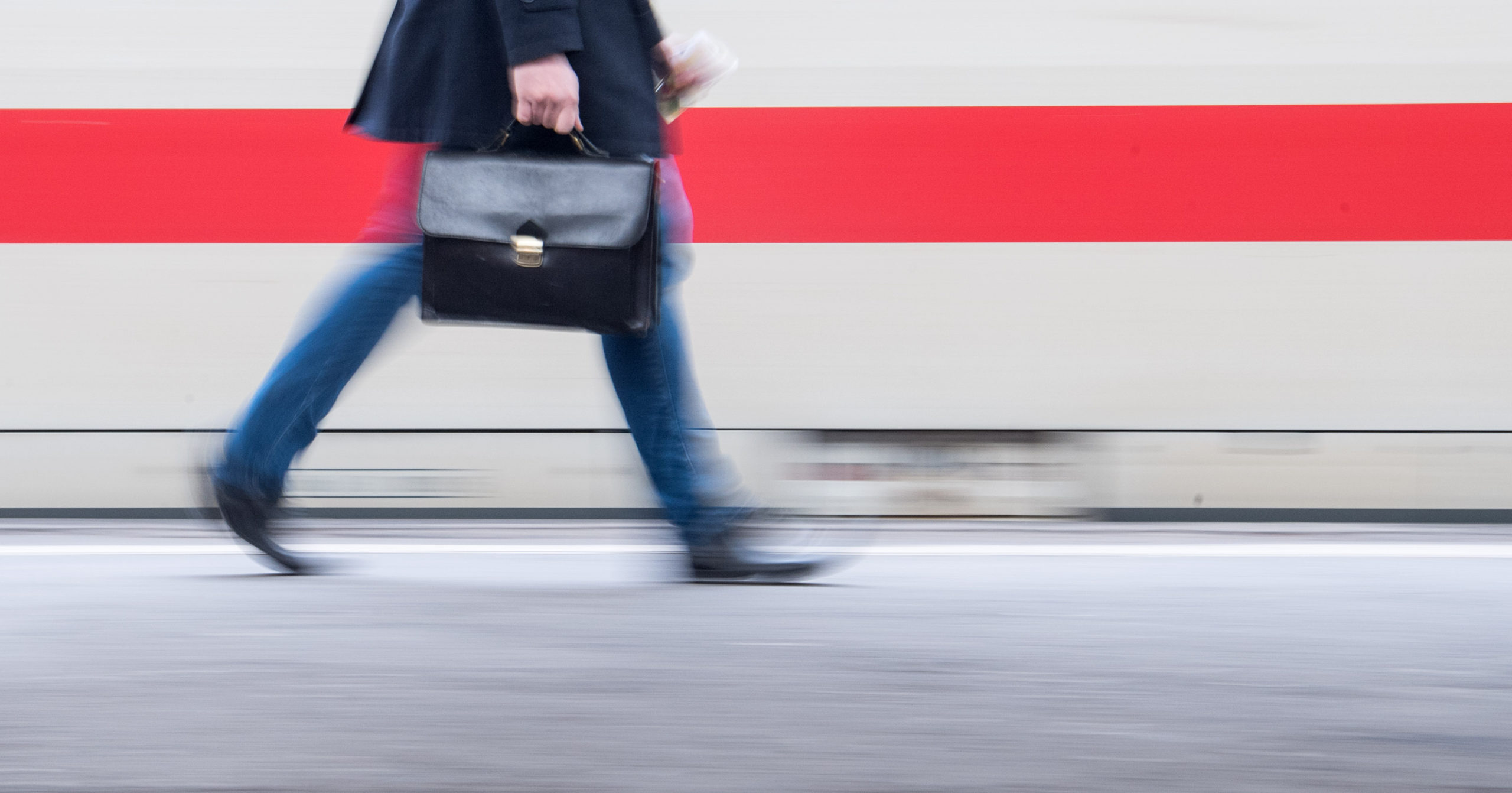 A man with a briefcase walks past an ICE train. 